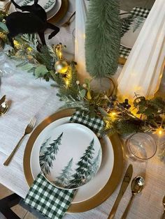 the table is set for christmas dinner with green and white plates, napkins, silverware and evergreen garland