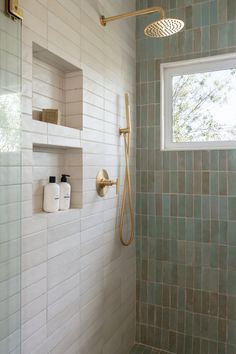 a bathroom with green tiled walls and white tile on the shower wall, along with shelves for toiletries