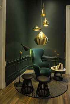 a living room with green walls and gold lamps hanging from the ceiling, along with two chairs