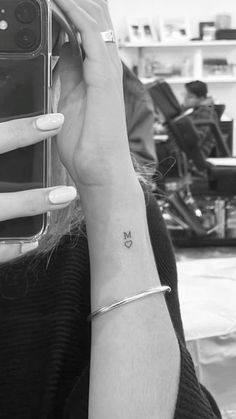 a woman with a small butterfly tattoo on her left wrist holding a phone up to her ear