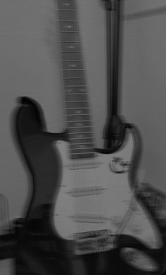 black and white photograph of an electric guitar with blurry image in the foreground