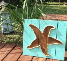 a wooden sign with a bird painted on it's side sitting on a deck