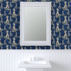 a bathroom sink sitting under a mirror next to a wall mounted faucet in front of a blue patterned wall