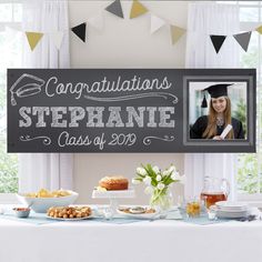 a graduation photo hanging on the wall above a table with food and drinks in front of it