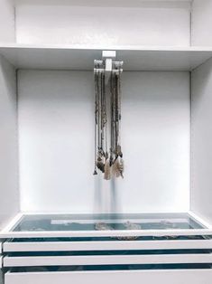 a white shelf with several necklaces hanging from it's sides in a room