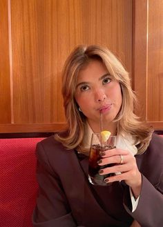 a woman sitting on a red couch holding a drink