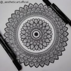 some black and white markers are laying on top of a paper with an intricate design