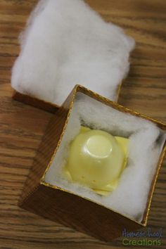 an open box with some yellow substance inside on top of a wooden table next to a pile of white fluffy material