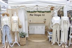 a display area with mannequins and other items on stands in front of a white tent