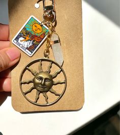 a hand holding a keychain with a sun design on the front and back