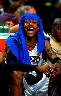 a man with a blue towel on his head sitting next to other men in the stands