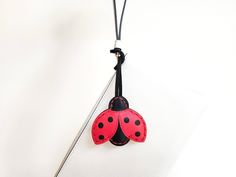 a red ladybug on a black cord attached to a white wall