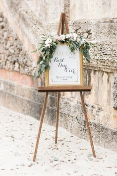 an easel with a sign and flowers on it