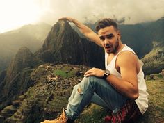 a man sitting on top of a mountain with his arms outstretched in front of him