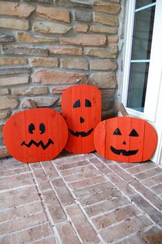 three carved pumpkins sitting on the front porch