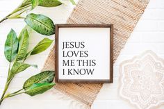 there is a sign that says jesus loves me this i know on it next to some plants