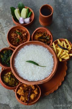 there are many bowls with food in them on the table, including rice and vegetables