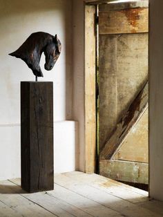 a horse head on top of a wooden block in front of an open barn door