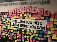 a bulletin board with sticky notes on it and words written in large letters that spell out kindness