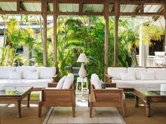 a living room filled with white furniture and lots of palm trees in the back ground