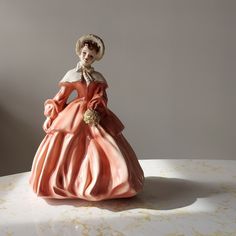 "The 'Abigail' figurine made by Florence Ceramics of Pasadena California  Sweet-faced lady wears mauve winter cloak and dress and fur trimmed bonnet. Trimmed with gleaming gold details and pink rosebuds in her hair. Excellent vintage condition. No chips, cracks, or crazing. Stands 8.5\" tall, 6.5\" wide, 5.5\" deep Base is incise marked 'Abigail' stamped 'Florence Ceramics Pasadena California Copyright' and marked with the initials 'DB' The Florence Ceramics Company was in business from 1942 thr Florence Ceramics, Winter Cloak, Pasadena California, Rose Buds, Gold Details, Fur Trim, Collectible Figurines, Her Hair, Florence