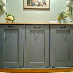 the sideboard is painted gray and has two vases with flowers on it,