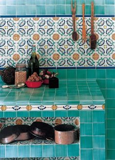 a blue tiled kitchen counter top with pots and pans on the shelf next to it