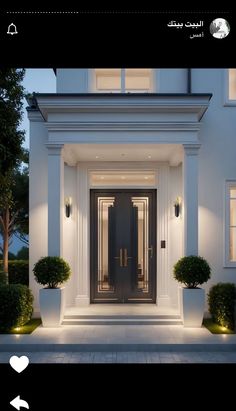 the front door of a white house with potted plants on either side and lights on