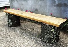 a wooden bench sitting in front of a cement wall with flowers growing on the side