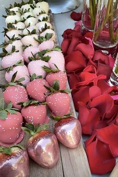 there are many different types of strawberries on the wooden table with flowers in vases