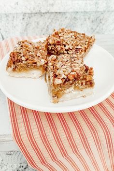 two pieces of pie on a white plate next to a red and white striped napkin