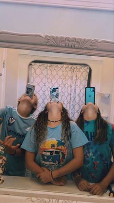 three people are taking selfies in front of a mirror with their cell phones up to their heads