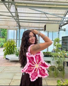 a woman holding a pink crocheted flower purse