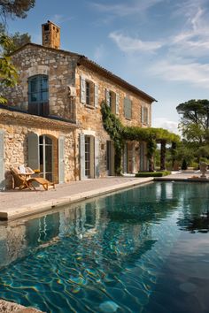 an outdoor swimming pool next to a stone house