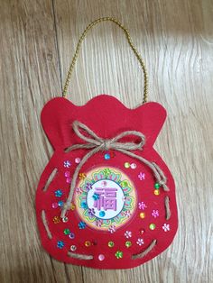 an ornament shaped like a red bag with flowers and letters on the front