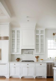 a kitchen with white cabinets and wood floors