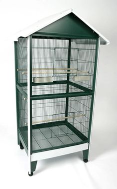 a green and white bird cage sitting on top of a shelf next to a wall