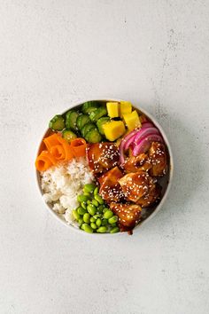 a white bowl filled with rice, meat and veggies on top of it