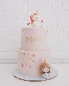 a pink cake with a unicorn figurine on top and the word mama written in gold