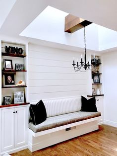 a living room with white walls and wood flooring on the wooden floor, built - in bookshelves