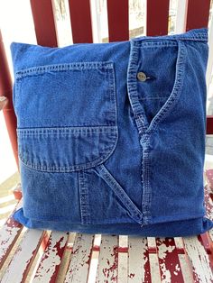 a blue jean pillow sitting on top of a wooden bench