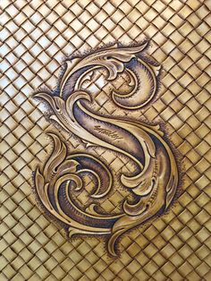 an intricate design on the side of a gold tiled wall with a bird in it's beak