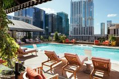 an outdoor swimming pool with lounge chairs and cityscape in the backround