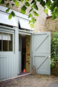 an open garage door in front of a brick building with green plants on the side