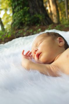 a baby is laying down on a white blanket