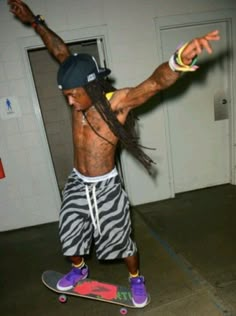 a man with dreadlocks is on a skateboard in a garage and has his arms stretched out