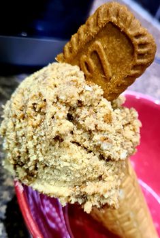 a scoop of ice cream in a pink bowl with a cookie on top and the end of it