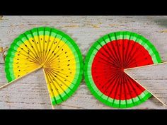 two colorful paper fans sitting next to each other on a wooden table with sticks sticking out of them