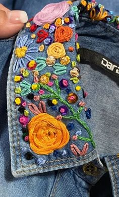 someone is stitching flowers on the back of their jean pants with beaded threads