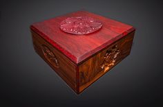 an intricately carved wooden box on a black background with red wood inlays